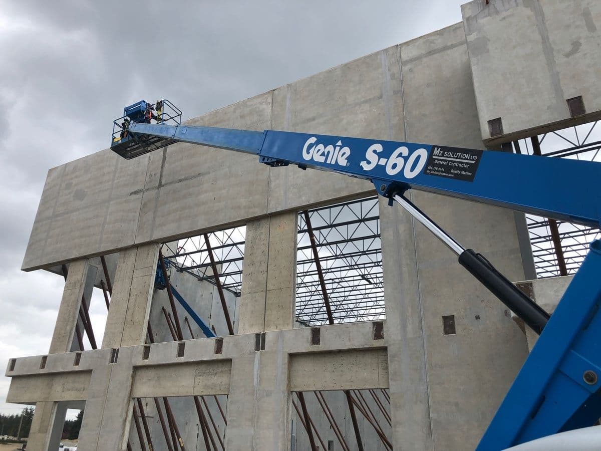 MZ Solution boom lift finishing a large tilt-up concrete commercial building