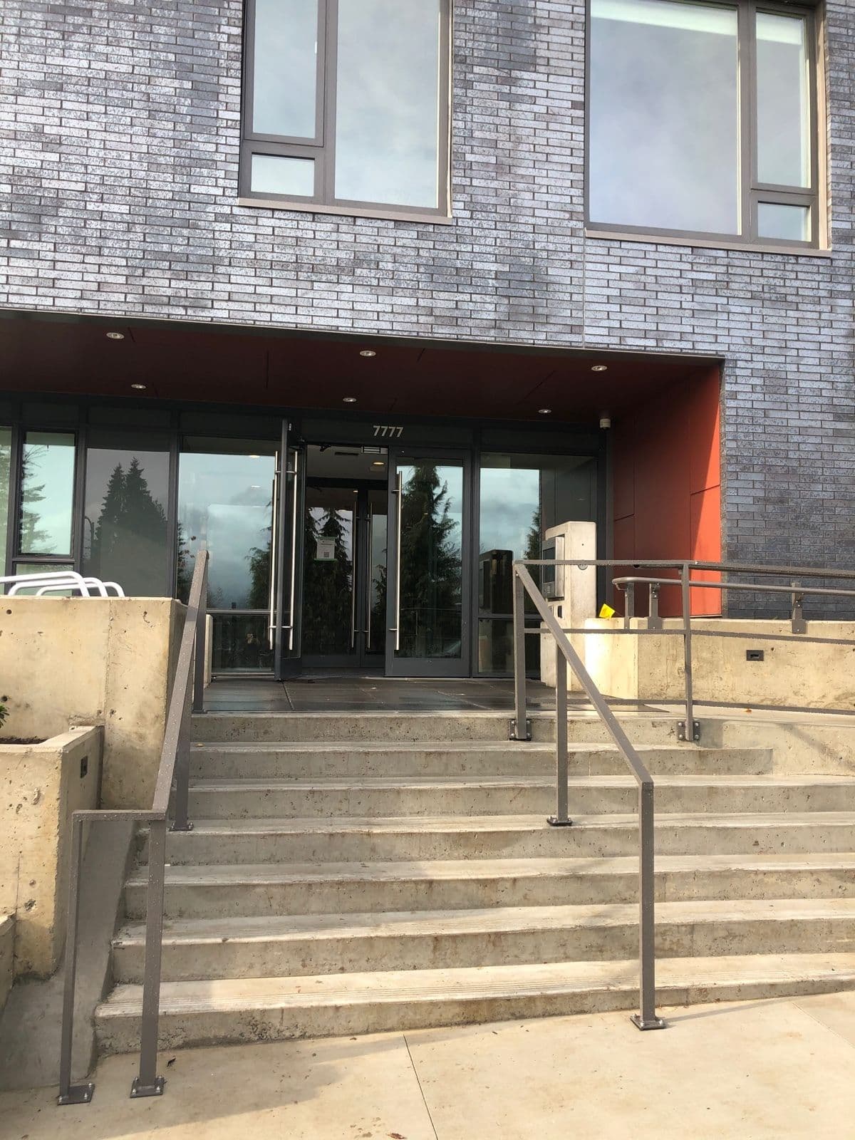 Concrete entrance stairs and steel handrails at a multi-unit building entrance