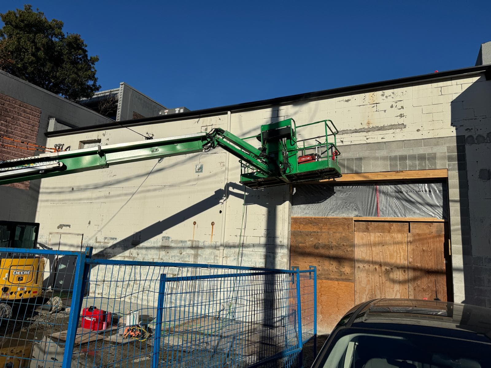 Boom lift prepping the upper section of a damaged painted exterior wall