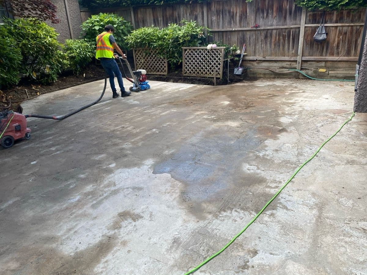 Concrete patio surface being ground and prepped for new pavers