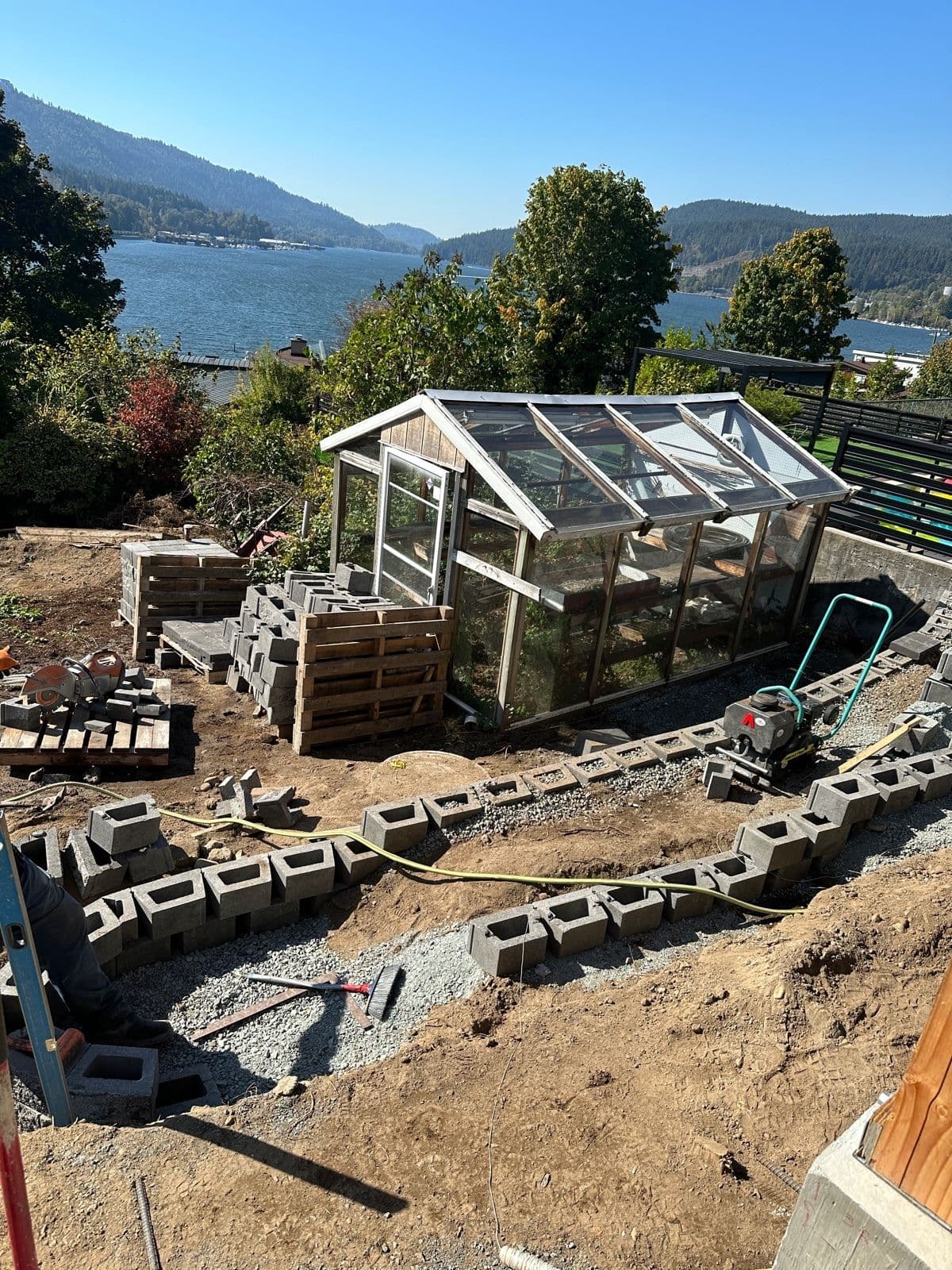 Curved concrete block retaining wall courses being laid with lake view behind