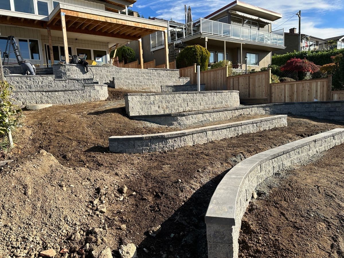 Terraced stone-finish retaining walls taking shape on a sloped lakeside yard