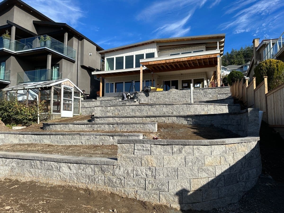 Tall curved retaining wall nearing completion behind a modern home