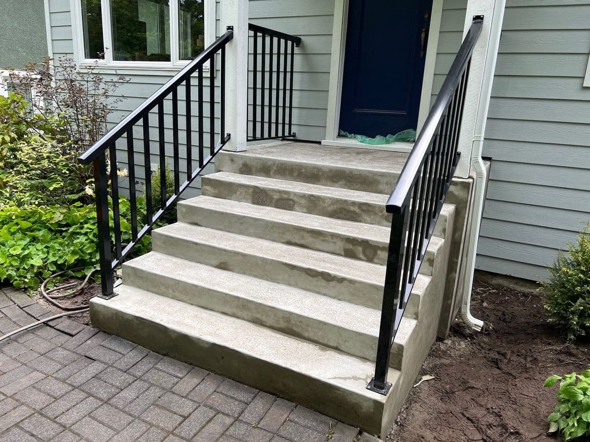 Finished front entrance steps with new black metal railings